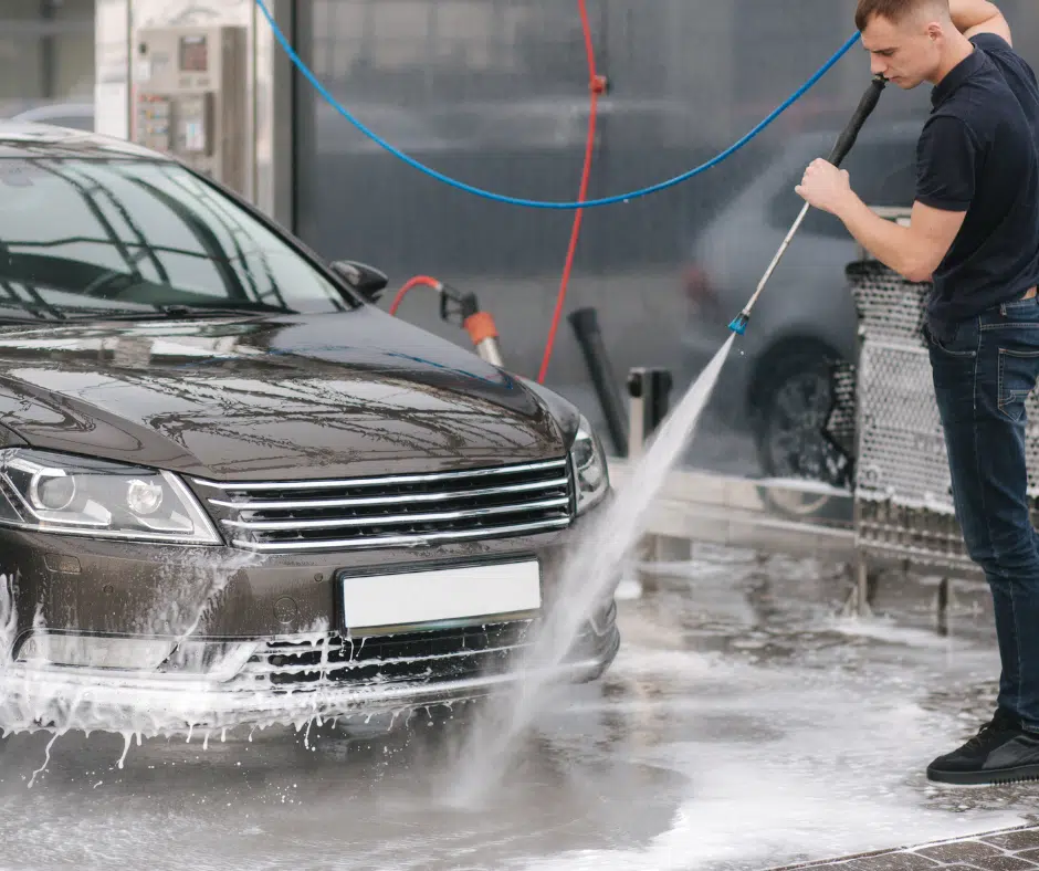 a car wash employee spraying off a car with a hose