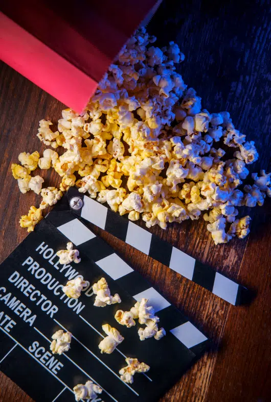 an image of movie theater products; popcorn and a clapperboard laying on the floor