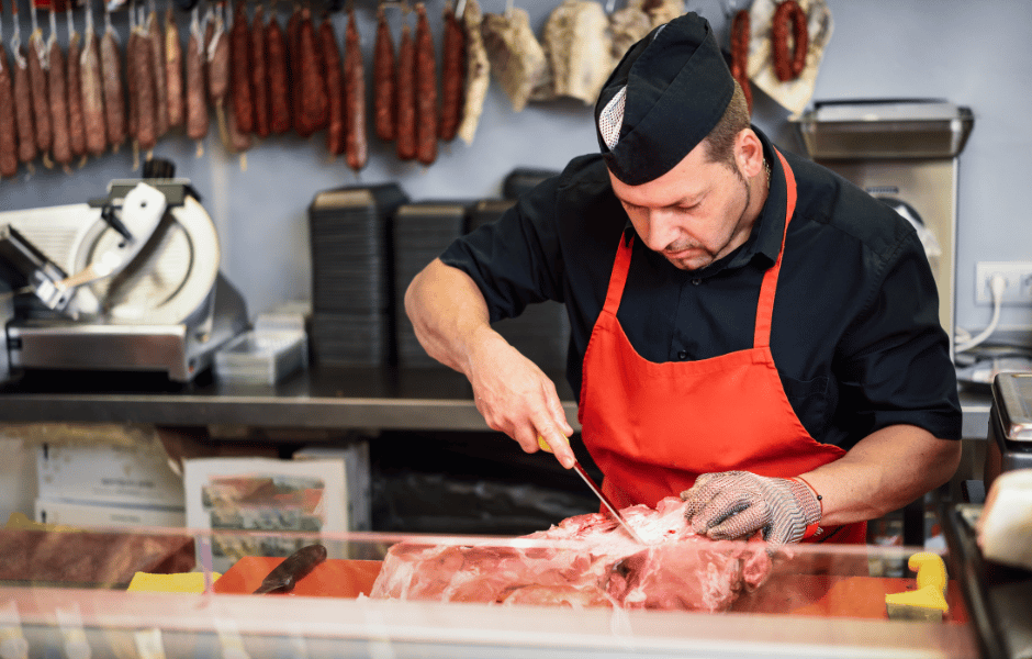 butcher shop owner cutting meat 