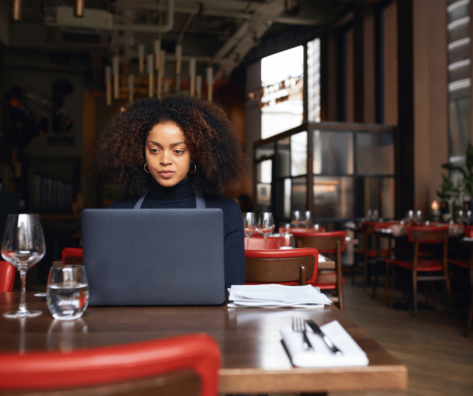 restaurant owner sitting at a table working on her laptop