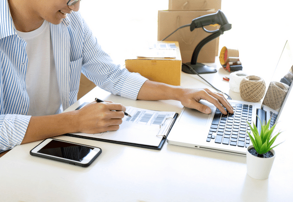 a person working at a desk on a laptop and looking at barcodes 