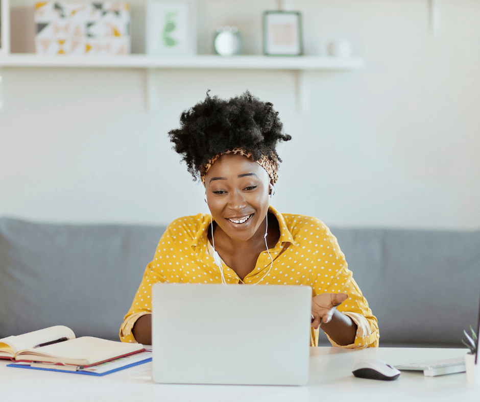 a woman happily working from home talking to someone on a laptop