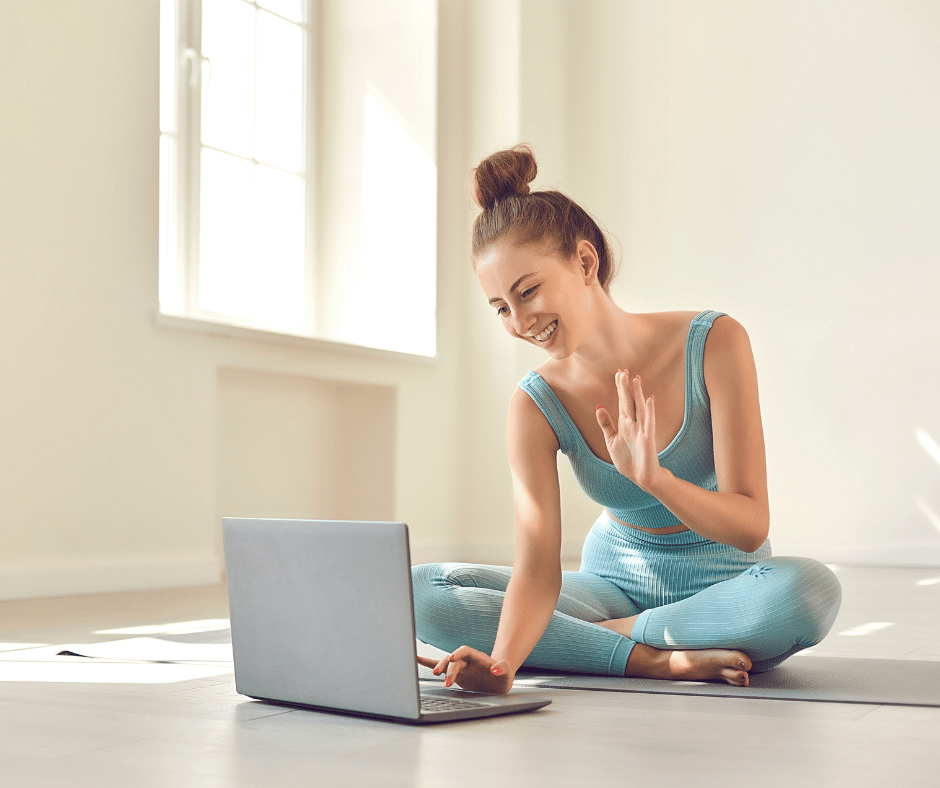 a girl inside of her home wearing a yoga outfit having a zoom call on a laptop