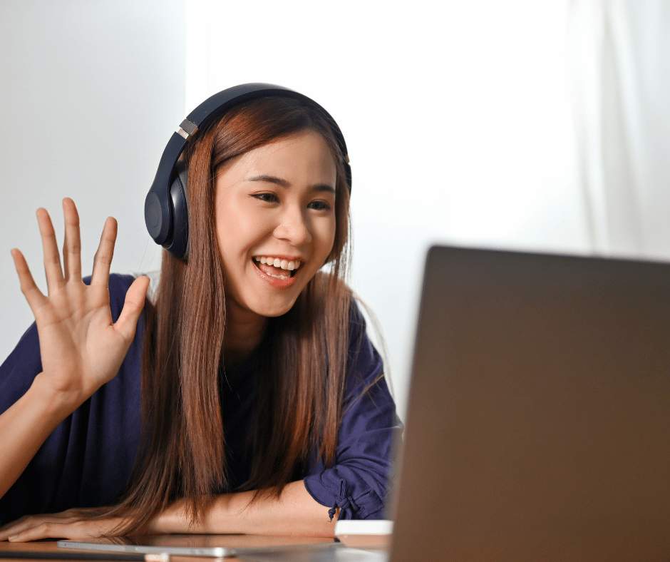 a woman working from home greeting someone on her laptop