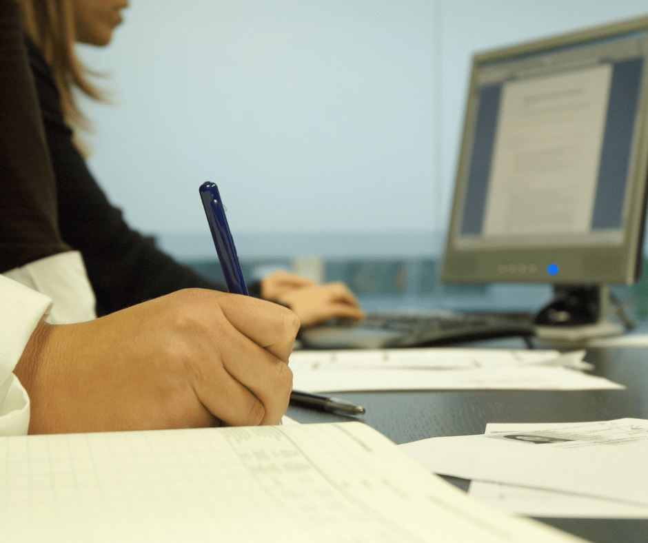 a photo of a woman working at a desk doing paperwork 