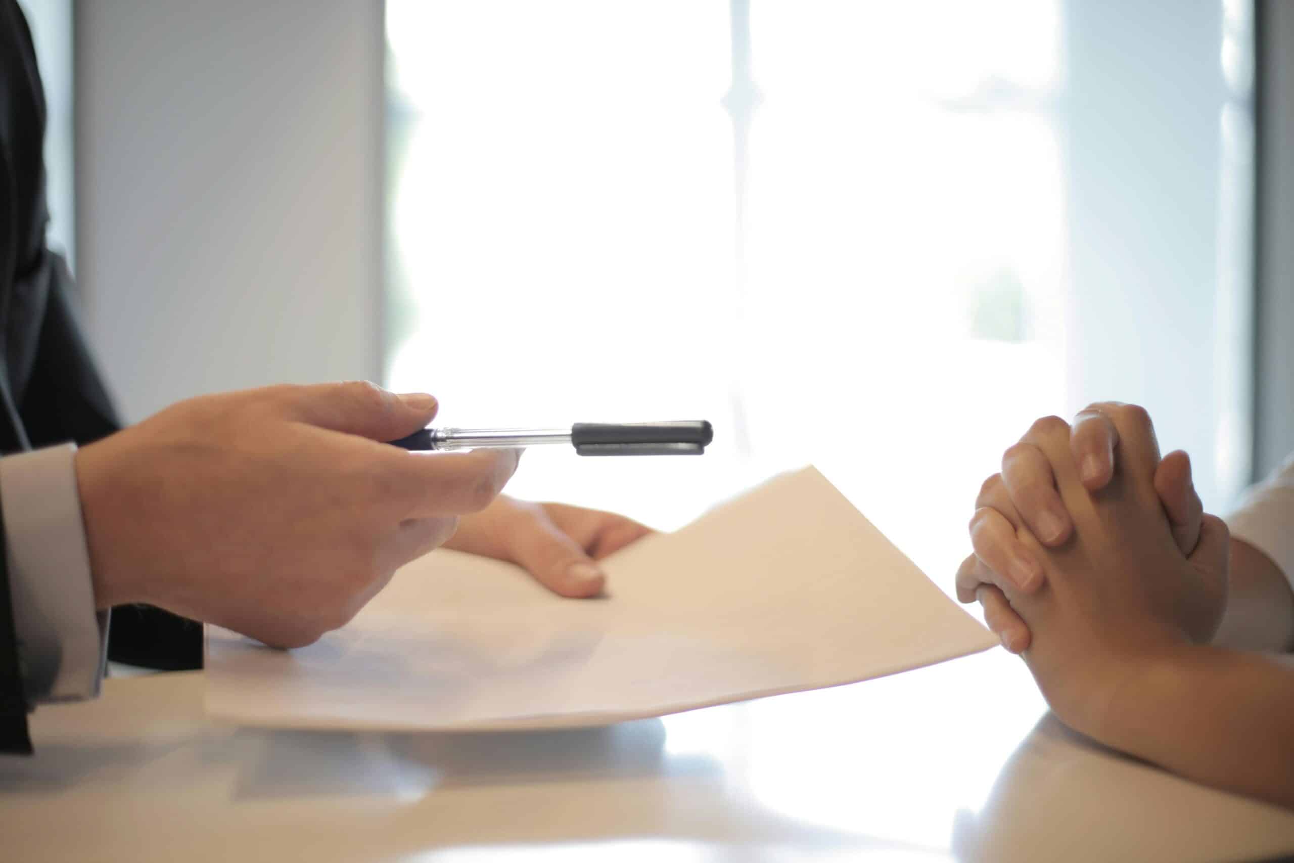 A businessman giving contract to woman to sign. 
